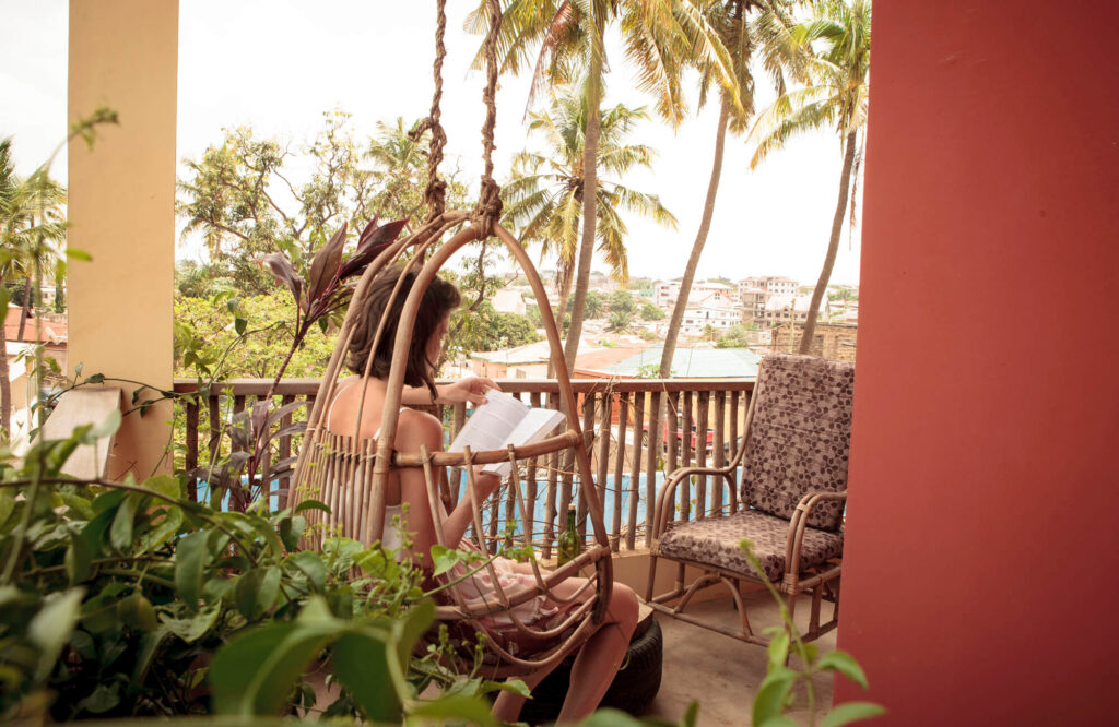 Frau liest auf dem Balkon eines Hotels in Accra